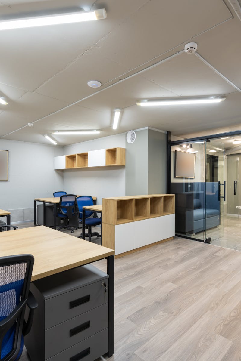 Spacious modern office interior with wooden desks, blue chairs, and ample lighting.